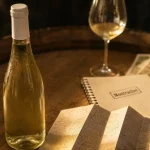 Grands crus Montrachet : bouteille de vin blanc sur tonneau en chêne, lumière dorée